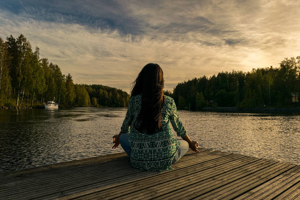 woman sitting on dock in yoga pose